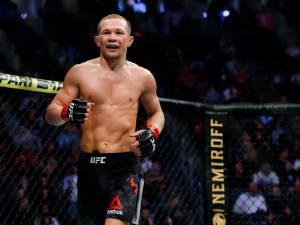 一位赤裸上身嘅MMA拳手喺UFC八角籠內同歡呼嘅人群一齊慶祝勝利。