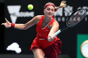 身穿紅色運動服的女子網球選手在比賽中用球拍擊打綠色球。 — 網球 壁紙