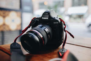 黑色Canon DSLR相機配紅色相機帶，放在城市環境中的木桌上。
