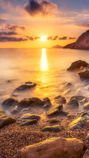 海上夕陽，發光的水面和霧氣籠罩的岩石海灘。