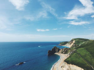海岸懸崖、沙灘和碧綠海洋，在晴朗天空下