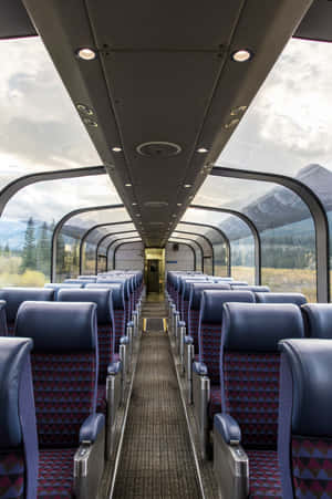 火車車廂，藍色圖案座椅，透過弧形窗戶欣賞山景。