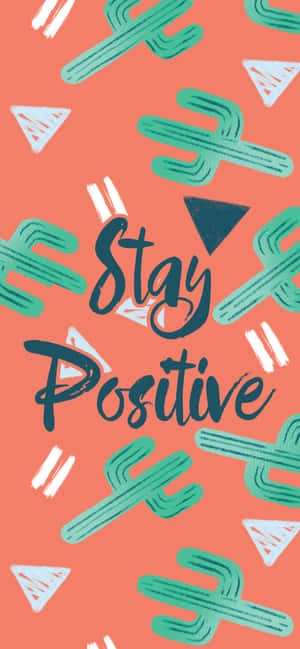 勵志短語 stay positive 被仙人掌和三角形圖案包圍在珊瑚色背景上 — Pixel 7a 壁紙