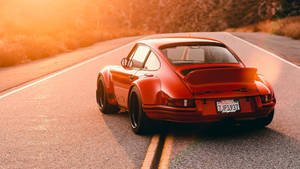 紅色保時捷911 Turbo在日落時分行駛在陽光照耀的道路上。