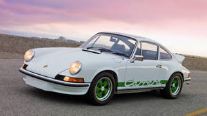 白色保時捷911 Carrera，綠色車輪，停在日落時分的路上。