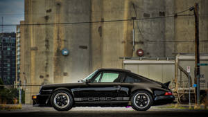 黑色保時捷911 Turbo停泊在都市環境中的混凝土牆旁邊。