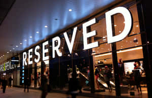 RESERVED服裝店的夜景，有玻璃窗和經過的行人。