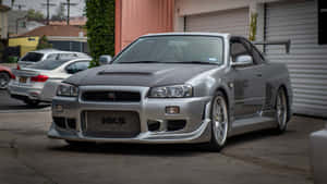 銀色日產Skyline R34跑車停泊在住宅車道上。