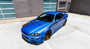 帶有金色條紋的藍色日產Skyline GT-R停在混凝土停車場。