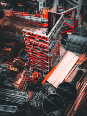 繁忙建築工地的俯視圖，帶有紅色棚架和鋼材。 — 2048x2732 壁紙