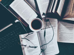 打開的書本、眼鏡、咖啡和手提電腦放在深色書桌上供學習使用。 — 溫習 壁紙