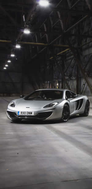 銀色McLaren跑車停放在燈光昏暗的工業倉庫中。 — 麥拿侖 720S 壁紙