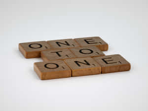木製 Scrabble 字母磚在白色背景上拼出 one to one