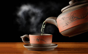 熱茶從陶瓷茶壺倒入木質表面上的相配杯子中。