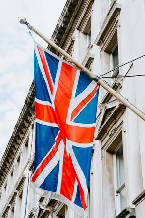 英國國旗在陰天下於城市建築上飄揚。