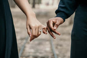 兩個人在鐵路軌道上手牽手，戴著訂婚戒指。 — 情侶 GIF 壁紙