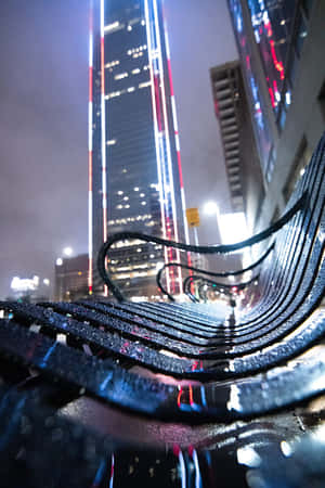 雨夜中反射霓虹燈光的濕彎曲長椅。