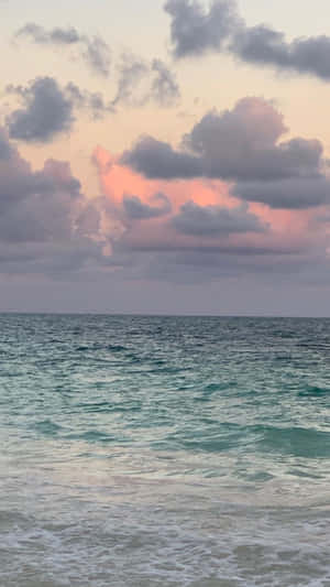 日落時分的海浪，天空中有粉紅色和灰色的雲彩。