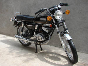 經典黑色Yamaha RX100電單車停泊喺混凝土上，靠近灰牆。 — 機車 壁紙