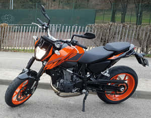 橙色和黑色KTM 390電單車停泊在圍欄附近的瀝青路上 — 機車 壁紙