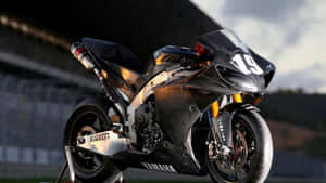 黑色和金色Yamaha賽車電單車，號碼19，在日落時的賽道上。 — 機車 壁紙