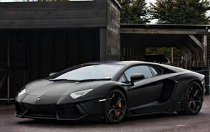 啞光黑色林寶堅尼 Aventador 停泊在木建築附近 — 蘭博基尼 壁紙