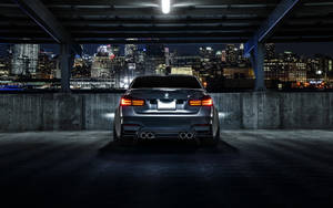 時尚的銀色BMW M5在夜間停泊，俯瞰著充滿活力的城市天際線。