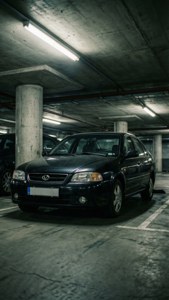 深色轎車停放在光線昏暗的混凝土地下停車場。