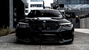黑色BMW M5跑車夜間停泊在城市街道上。