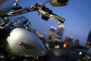 銀色Harley-Davidson電單車，帶有鍍鉻細節，背景是黃昏時模糊的城市天際線。 — 哈雷戴維森 壁紙