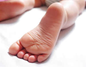 嬰兒的腳在白色毯子上