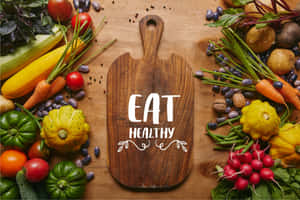 新鮮蔬菜和香草圍繞著一塊帶有「EAT HEALTHY」字樣的木製砧板擺放。