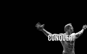 肌肉男舉起啞鈴，帶有「CONQUER」文字疊加。