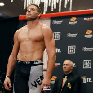 肌肉發達的MMA拳手穿著Venum短褲，在稱重活動中，身後有贊助商標誌。 — 1:1 壁紙