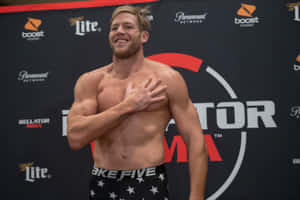 赤裸上身的MMA戰士在稱重活動中微笑著將手放在胸前。