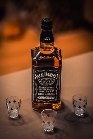 一瓶Jack Daniel's威士忌，配三個烈酒杯，放在桌子上。