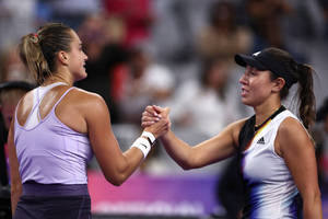 兩名女網球運動員比賽結束後微笑握手。
