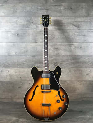旭日色Gibson ES-335電結他放在灰色木牆上