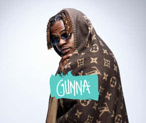 戴太陽眼鏡的男子披著 Louis Vuitton 毛毯，帶有 'Gunna' 文字覆蓋。