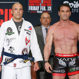 兩名男性MMA拳手在稱重活動中，一人身穿白色道服，另一人身穿黑色短褲。