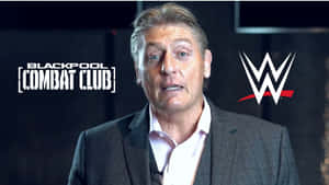 男子身穿西裝在WWE Blackpool Combat Club活動中發言。
