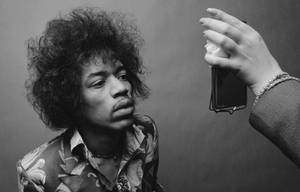 Jimi Hendrix 在工作室肖像中抬頭望向一隻拿著手機的手。