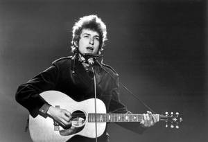 Bob Dylan 在舞台上彈奏木結他並對著咪高峰唱歌。 — 黑白 壁紙