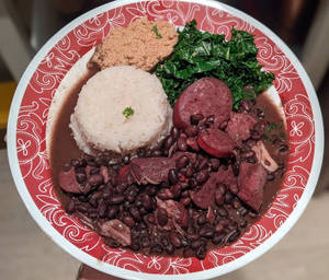 巴西黑豆燉肉菜餚，配有豆、飯和青菜，放在圖案碟子上