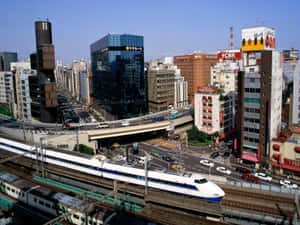 一列高速列車穿過繁華的日本城市景觀，高樓大廈和繁忙街道盡收眼底。 — 桌面美學 壁紙