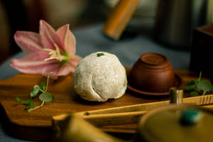 一個撒上糖粉的麻糬和一朵粉紅花放在木茶托盤上。 — 甜品 壁紙