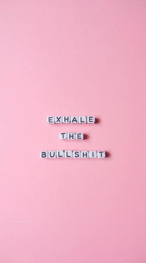 白色字母瓷磚在粉紅背景上拼出 exhale the bullshit