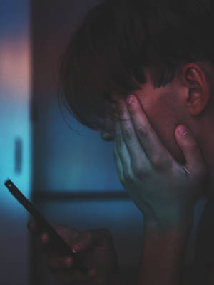 人在昏暗藍光下拿著電話並遮住臉