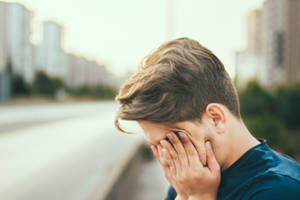 年輕男子在街上痛苦掩面