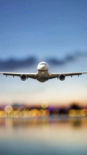飛機在黃昏時分接近城市上空準備降落，燈光模糊。